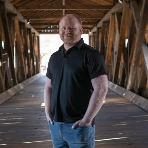 William Donahue, owner of ProsperousDad Consulting, standing on a covered wooden bridge